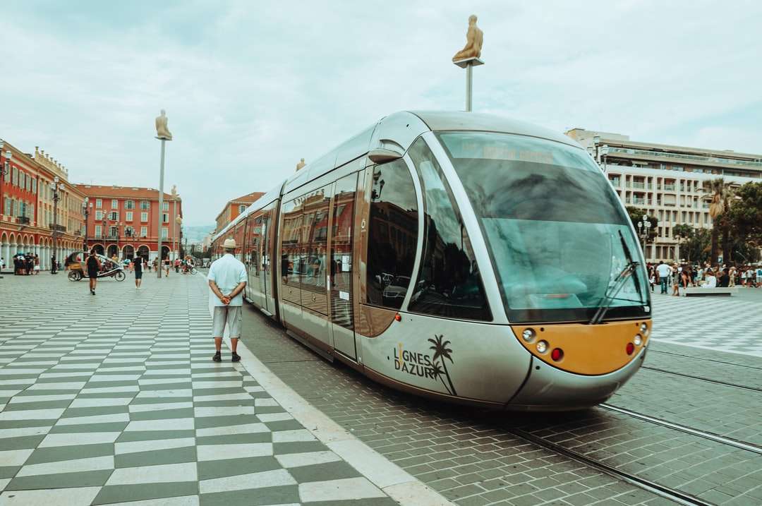mensen lopen op de stoep in de buurt van witte en gele tram legpuzzel online