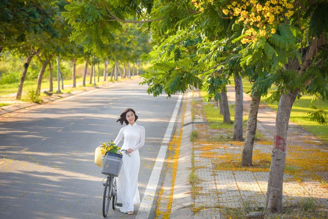 Frau im weißen Langarmhemd, das Fahrrad auf Straße fährt Online-Puzzle