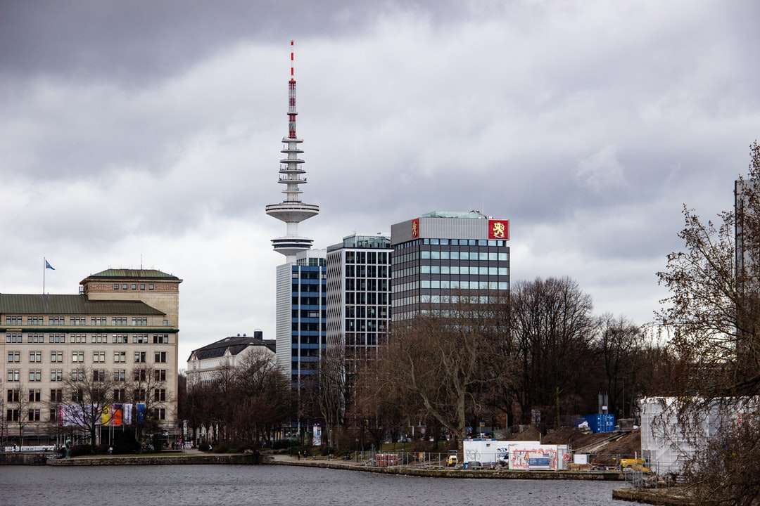 torre branca e vermelha perto de edifícios da cidade sob nuvens brancas puzzle online