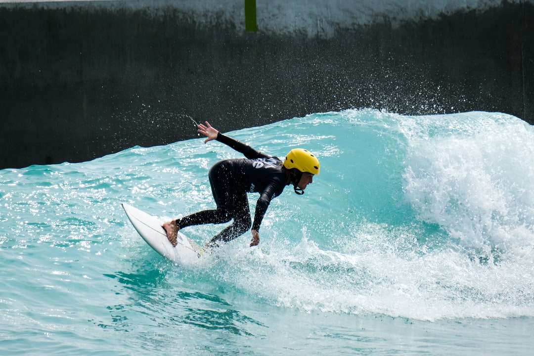 Mann im schwarzen nassen Anzug mit weißem Surfbrett tagsüber Online-Puzzle