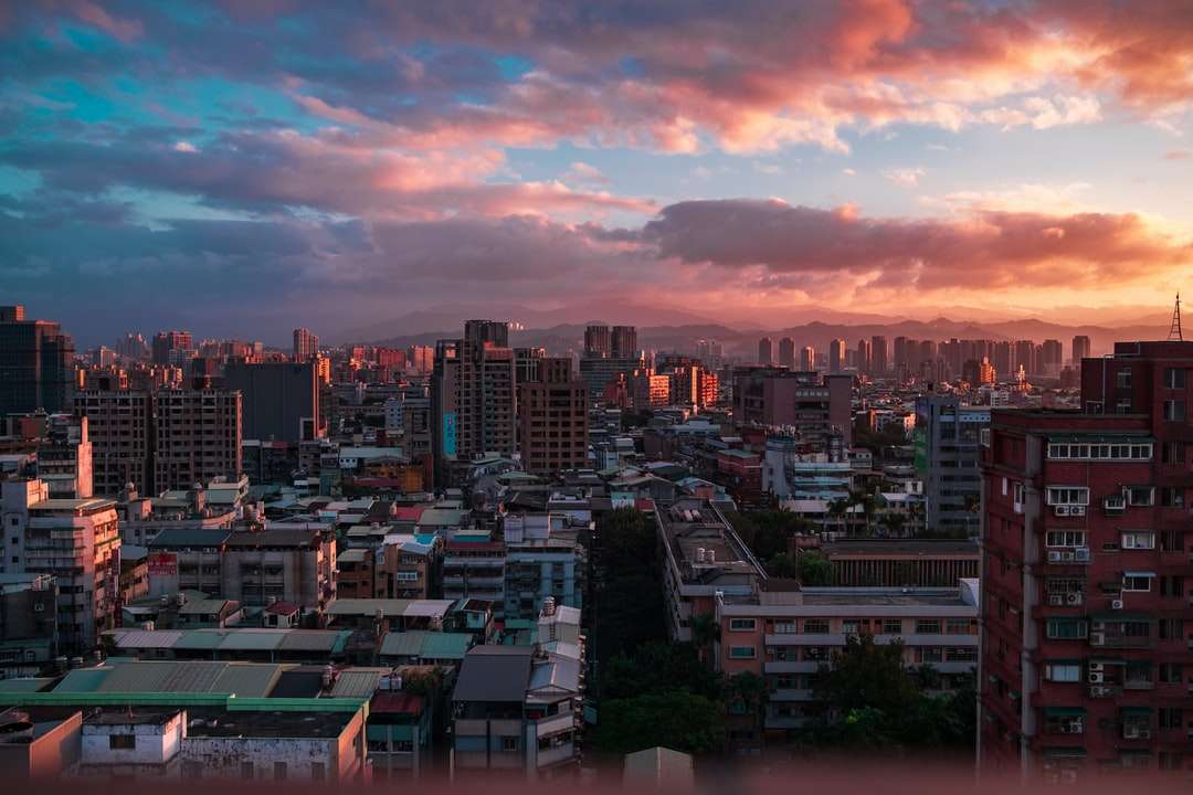 Városi skyline narancssárga és szürke felhős ég alatt naplementekor kirakós online