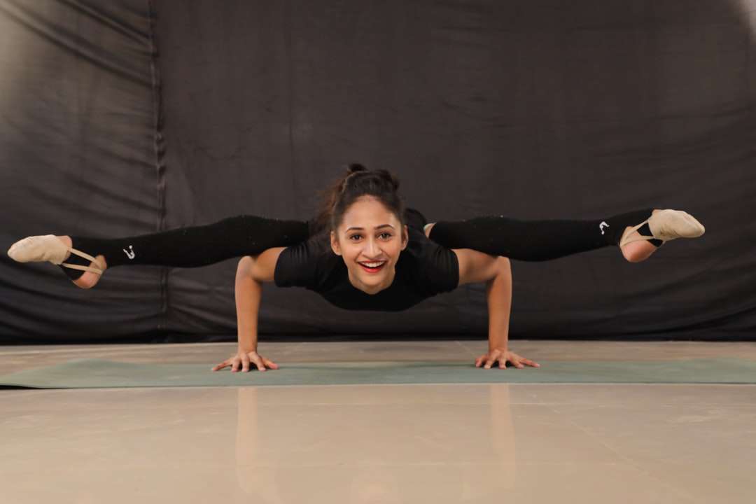 Femme en T-shirt noir et pantalon noir faisant du yoga puzzle en ligne