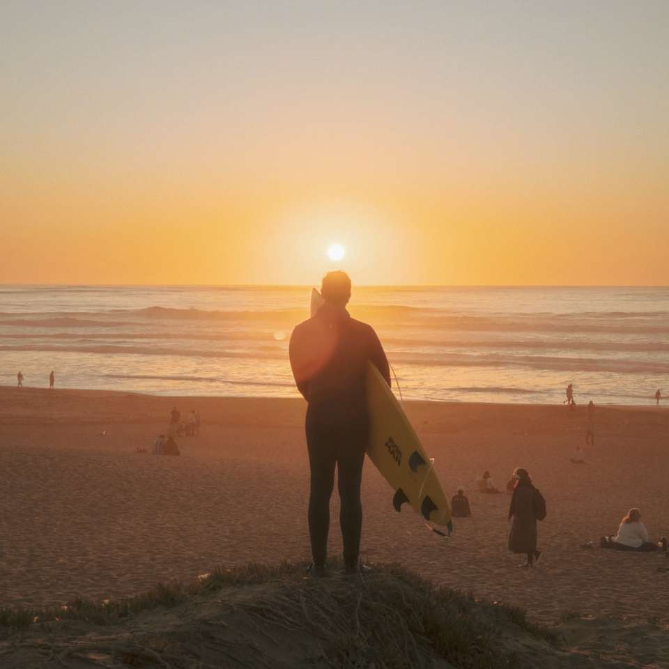 Silhouette des Mannes, der Surfbrett hält, der auf Strand geht Online-Puzzle
