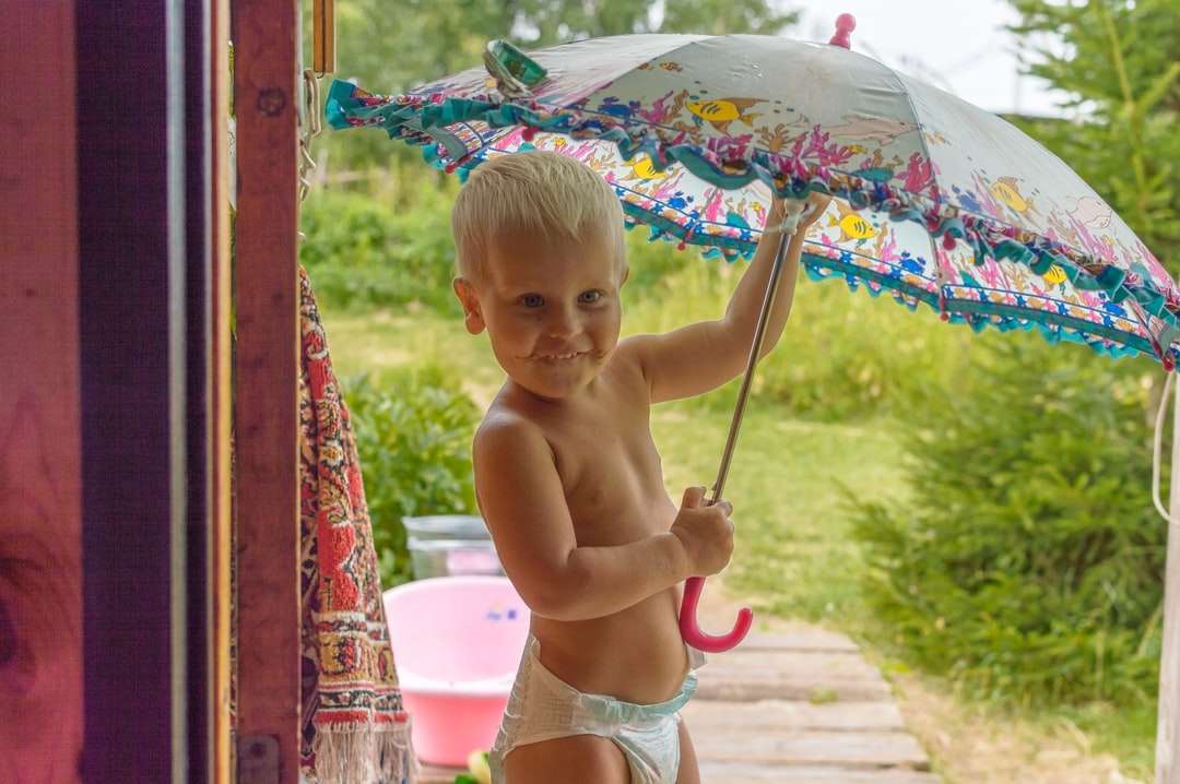 Bebé en topless con paraguas mientras está sentado rompecabezas en línea