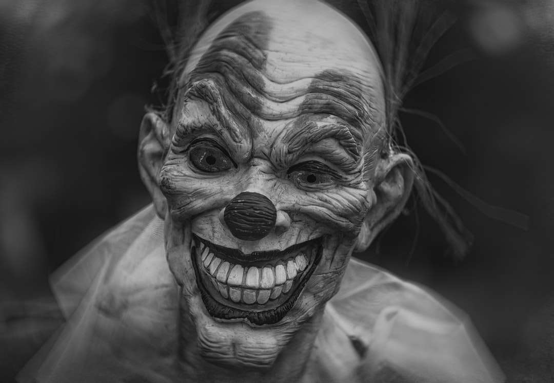 Photographie en niveaux de gris de personne portant un masque de clown puzzle en ligne