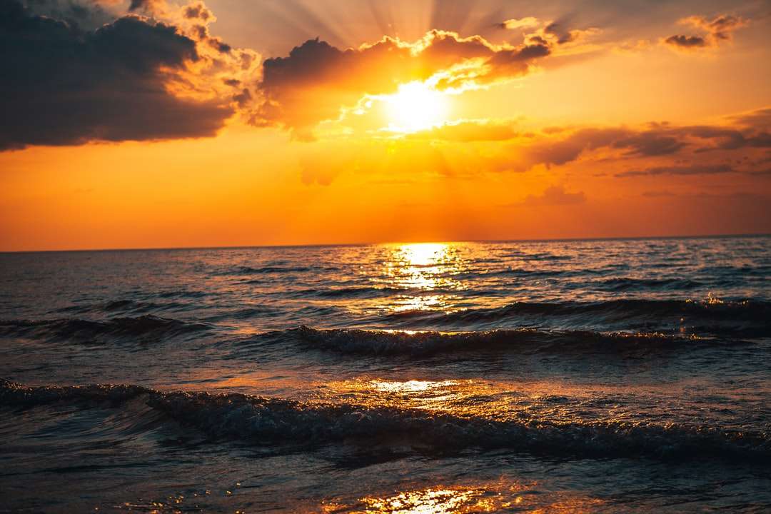 Ondas do mar batendo na praia durante o pôr do sol puzzle online