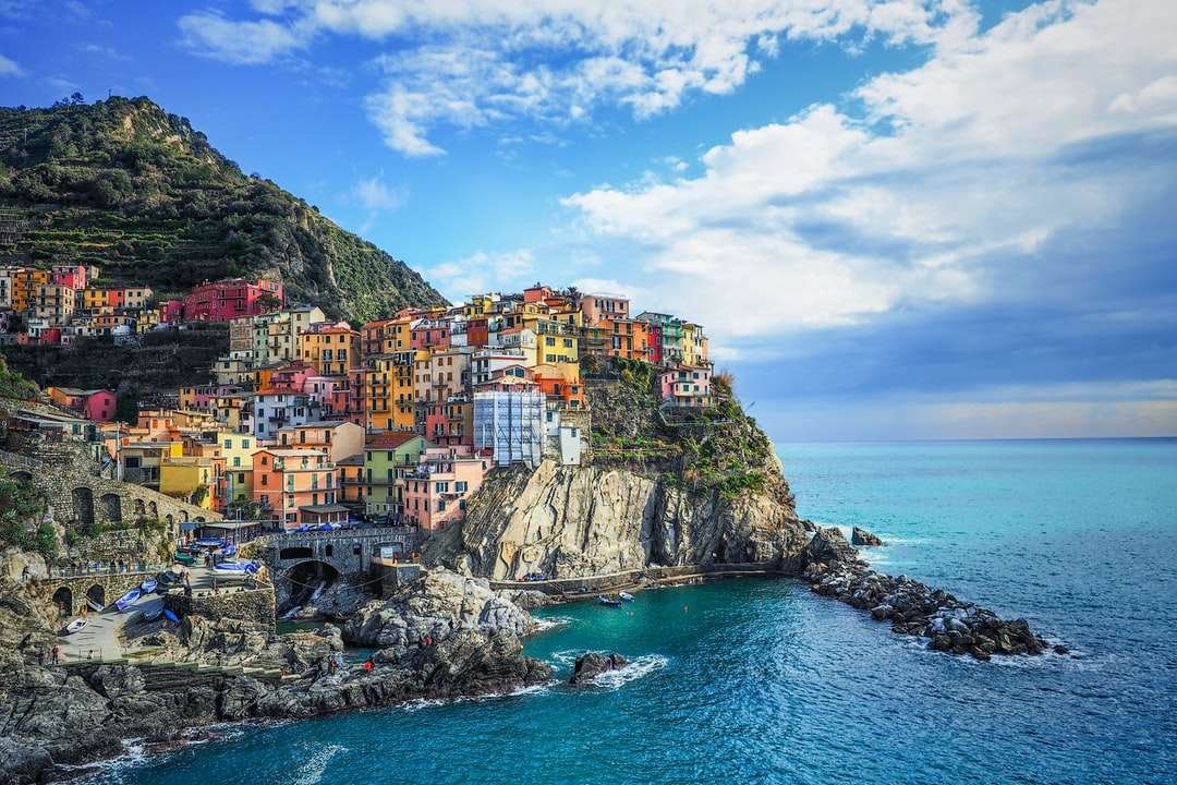 Casas na montanha ao lado do mar sob o céu azul durante o dia puzzle online
