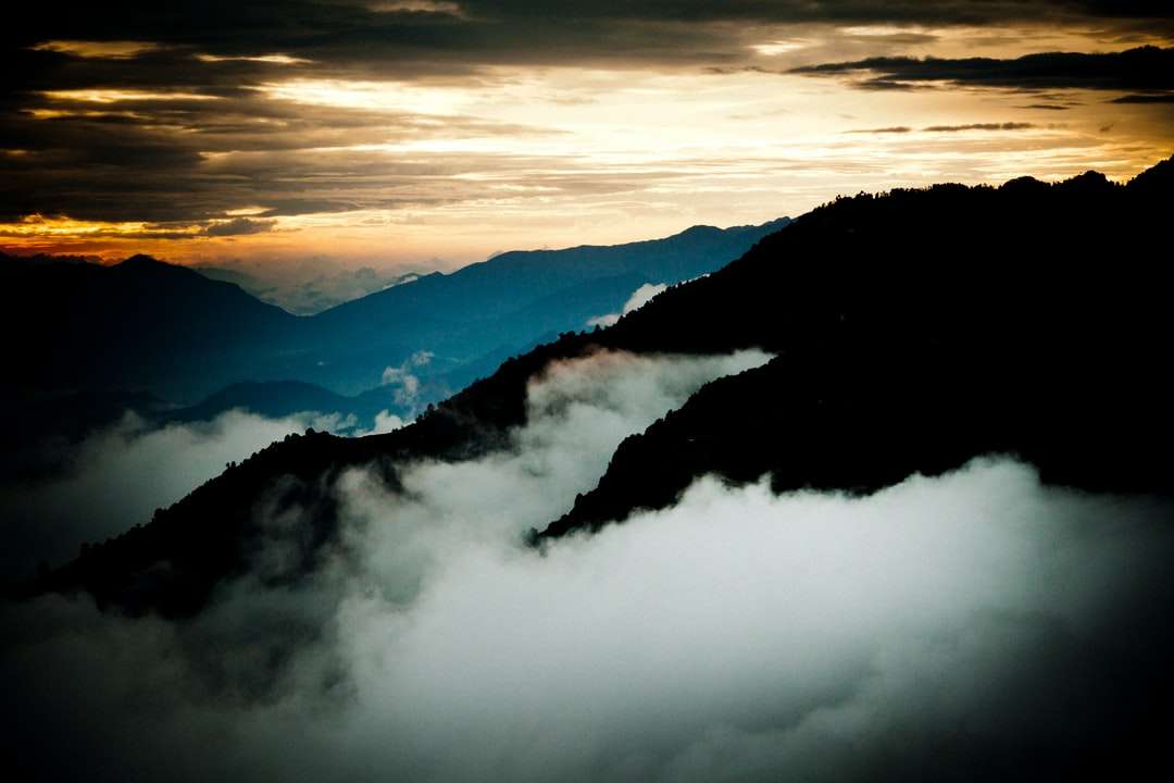 Berg täckt med moln under dagtid Pussel online