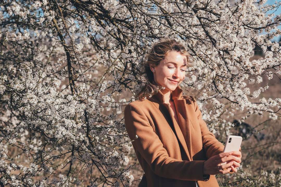 Frau im braunen Mantel, der an der Tageszeit in der Nähe des braunen Baums steht Online-Puzzle