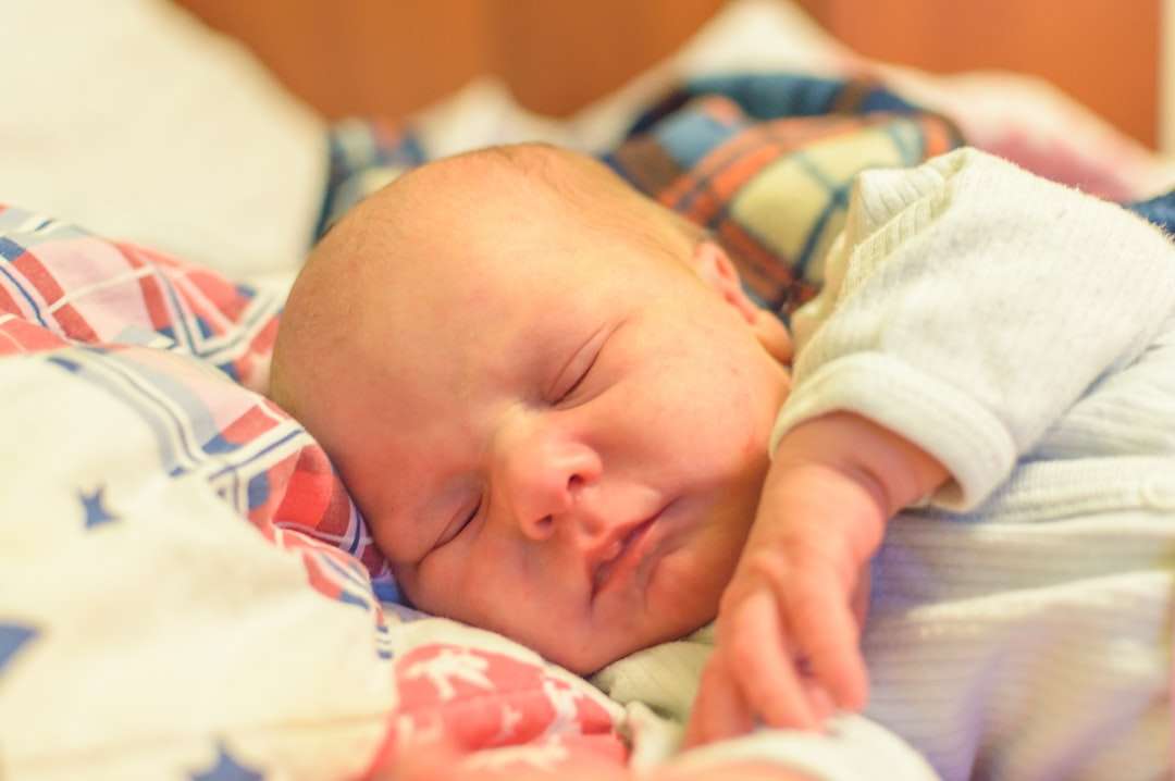Bebé en blanco y azul Onesie acostado en la cama rompecabezas en línea