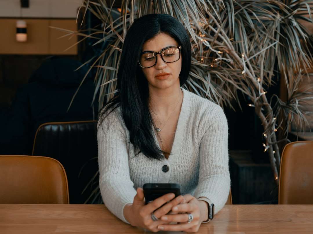 Γυναίκα σε λευκό ζακέτα που κατέχουν μαύρο smartphone online παζλ