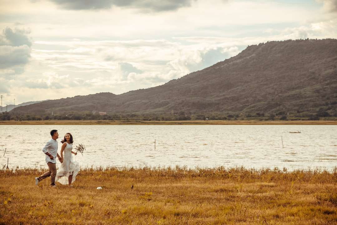 Nő fehér ruhában ül a zöld fű mező közelében tó kirakós online