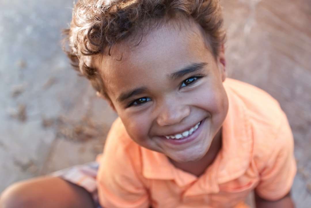 Junge im orangefarbenen Poloshirt lächelnd Online-Puzzle