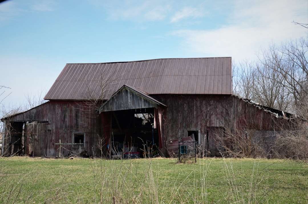 Barn en bois marron sur le champ d'herbe verte sous le ciel bleu puzzle en ligne