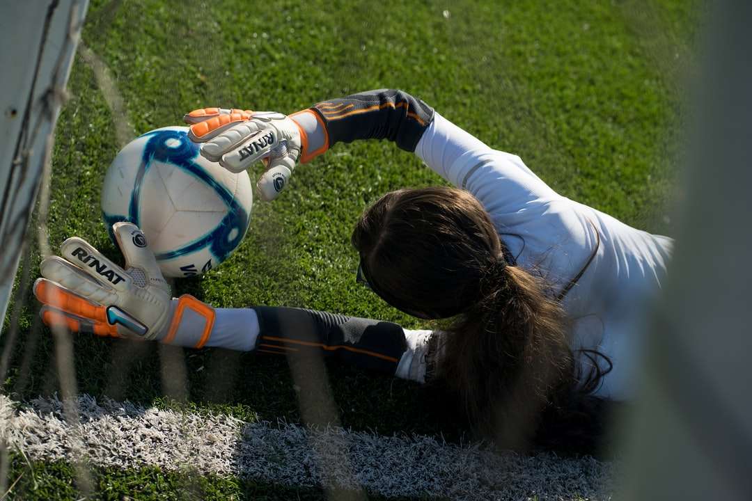 Mädchen im weißen Langarmhemd-Hemd, das Fußball auf Feld spielt Online-Puzzle