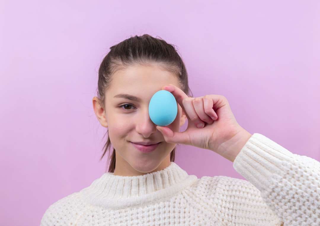 Femme en pull blanc tenant un œuf bleu puzzle en ligne