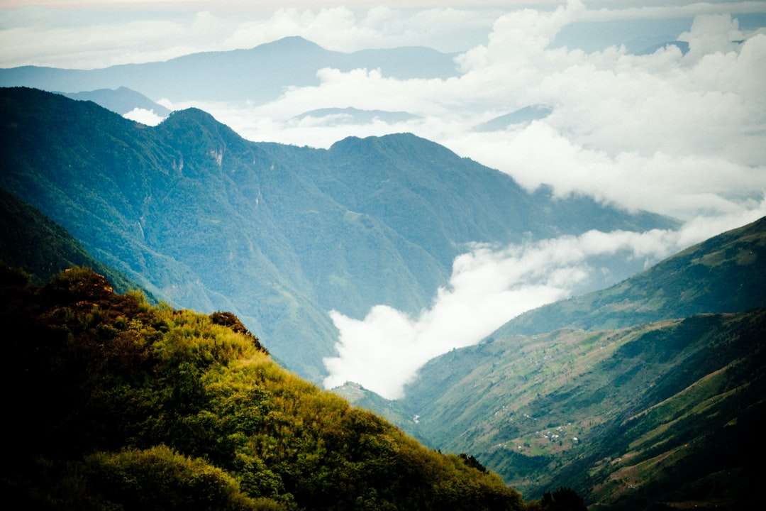 Gröna och bruna berg under vita moln under dagtid Pussel online