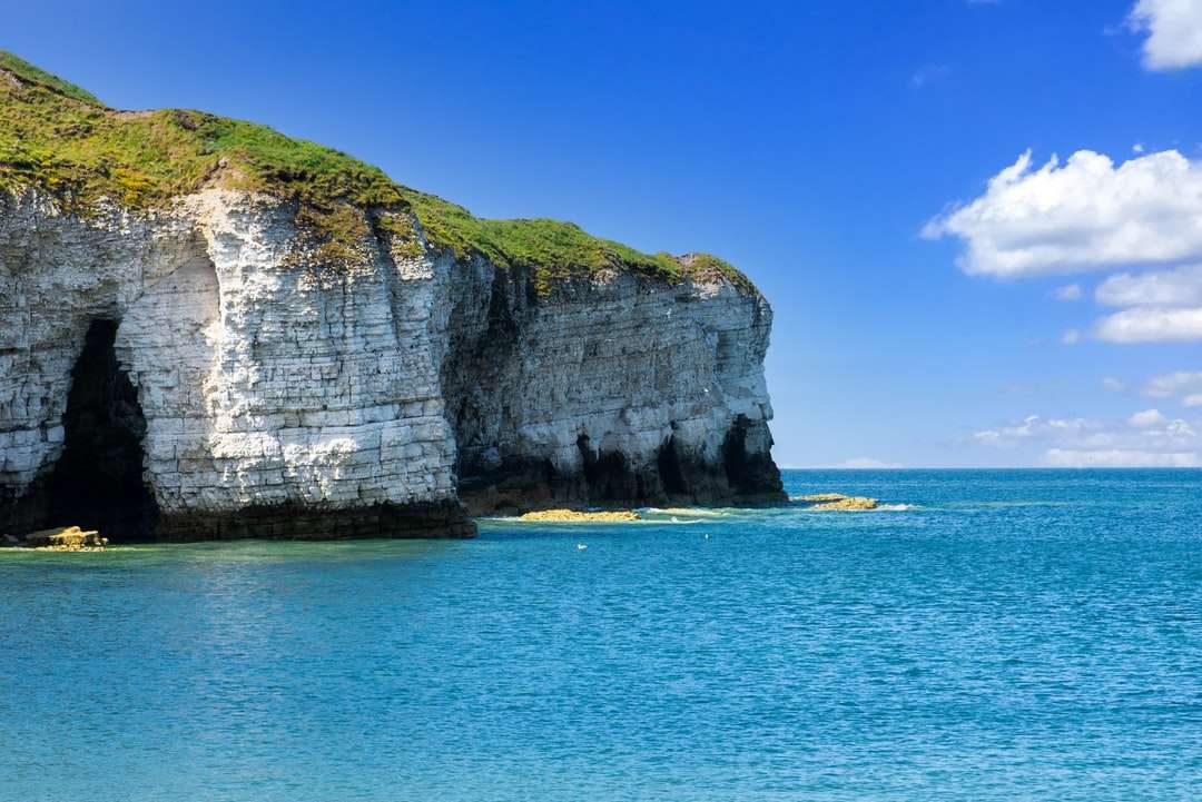 Mont marron et verte à côté de la mer bleue sous un ciel bleu puzzle en ligne
