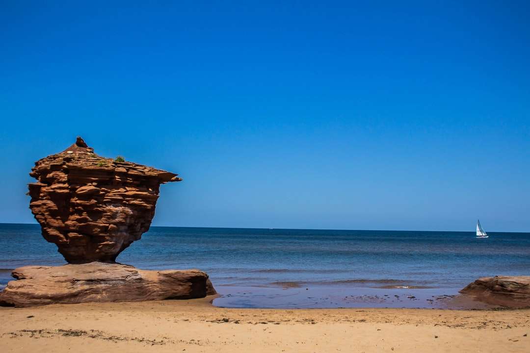 Formação de rocha marrom na praia durante o dia quebra-cabeças online