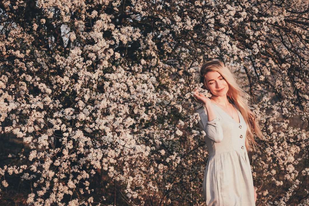 Жена в бяла рокля, стояща на бяло поле на цветя онлайн пъзел
