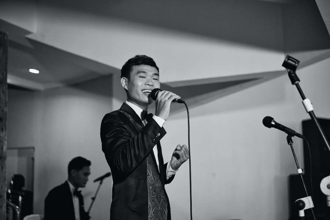 Mann im schwarzen Anzug singt auf der Bühne Online-Puzzle