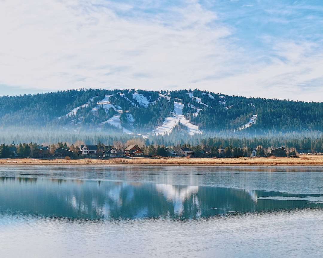 Snow acoperit de munte lângă lac sub cerul noros puzzle online