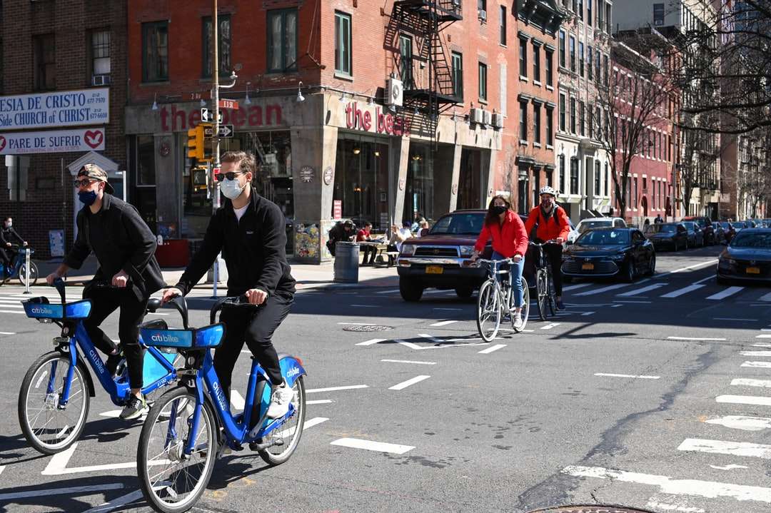 Omul în jacheta neagră de echitatie bicicletă albastră pe stradă jigsaw puzzle online