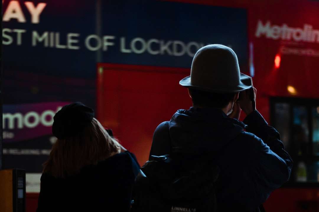 мъж и жена в черно яке, стоящи пред червената стена онлайн пъзел