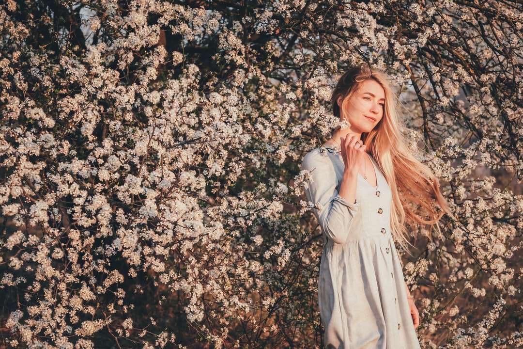 Žena v bílých šatech stojící vedle bílých květů online puzzle