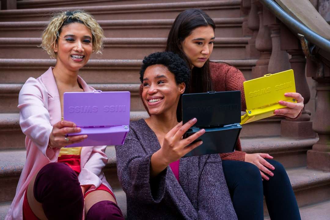 Vrouw in paarse trui die iPad naast vrouw houden online puzzel