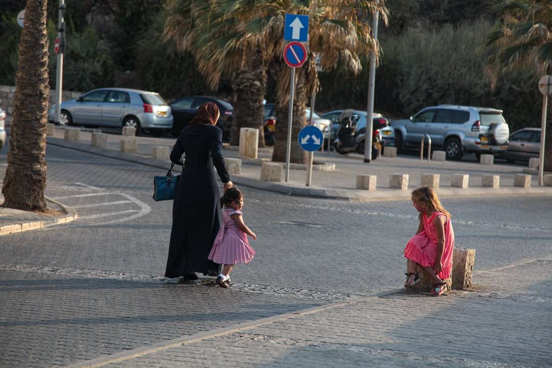 Kvinna i svart hijab går på trottoaren under dagtid pussel på nätet
