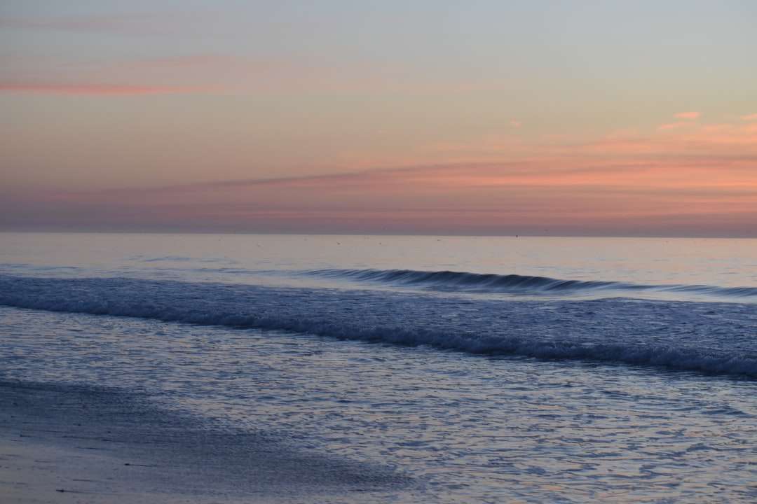 океанські хвилі розбиваються на берег під час заходу сонця пазл онлайн