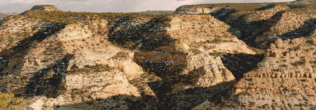 Bruine rotsachtige berg onder grijze hemel overdag online puzzel