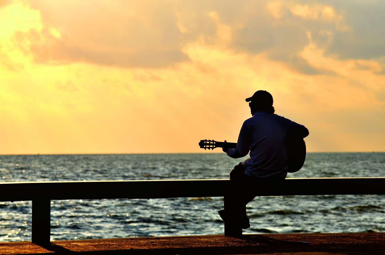 Un homme avec une guitare au coucher du soleil puzzle en ligne