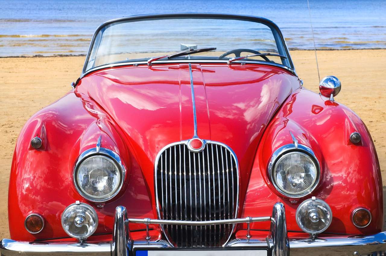 Oude klassieke rode auto op het strand legpuzzel online