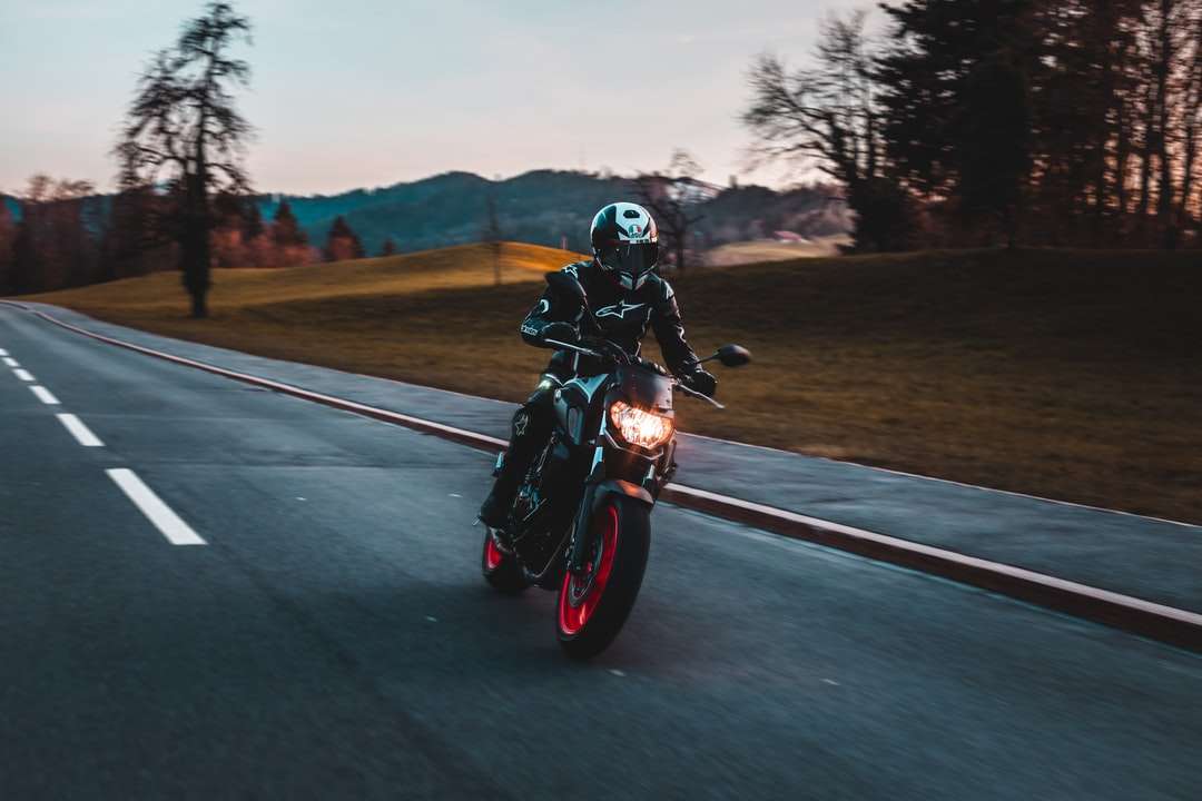 Човек в черната шлем езда мотоциклет по пътя през деня онлайн пъзел