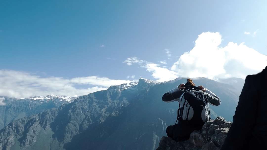 Uomo in giacca nera prendendo foto di montagna innevata puzzle online