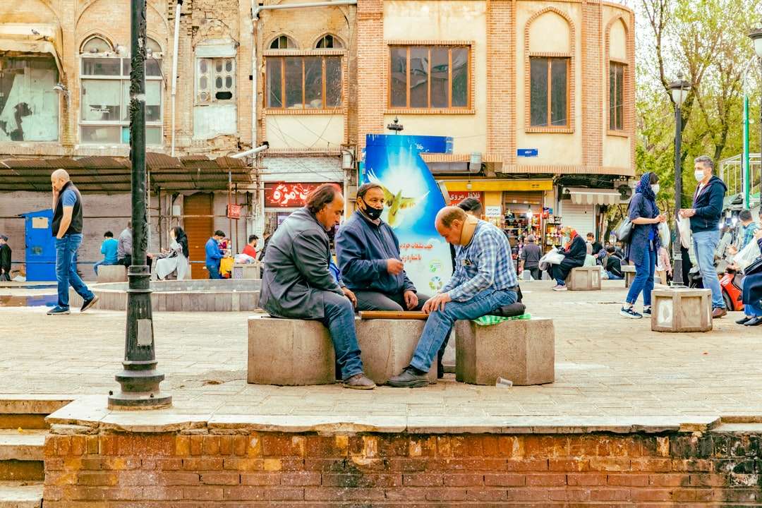 Omul în albastru Denim Jeans Sitting pe banca de beton gri puzzle online