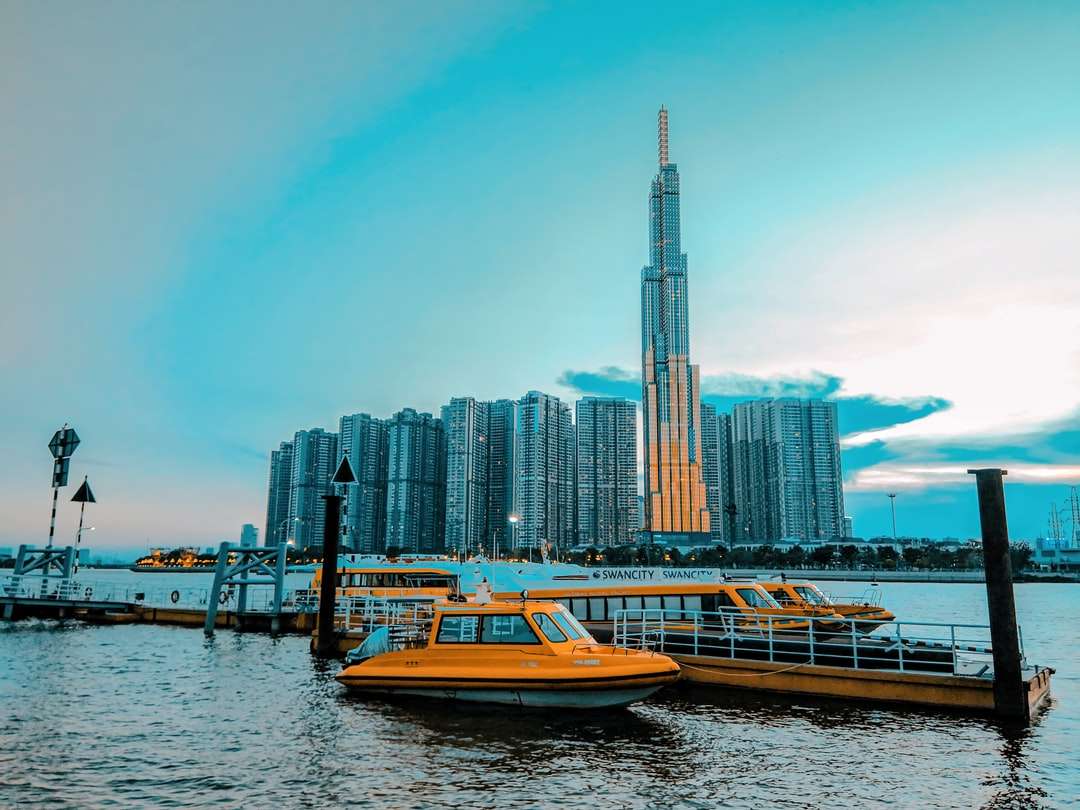 Barca albă și brună pe apă în apropierea clădirilor orașului puzzle online