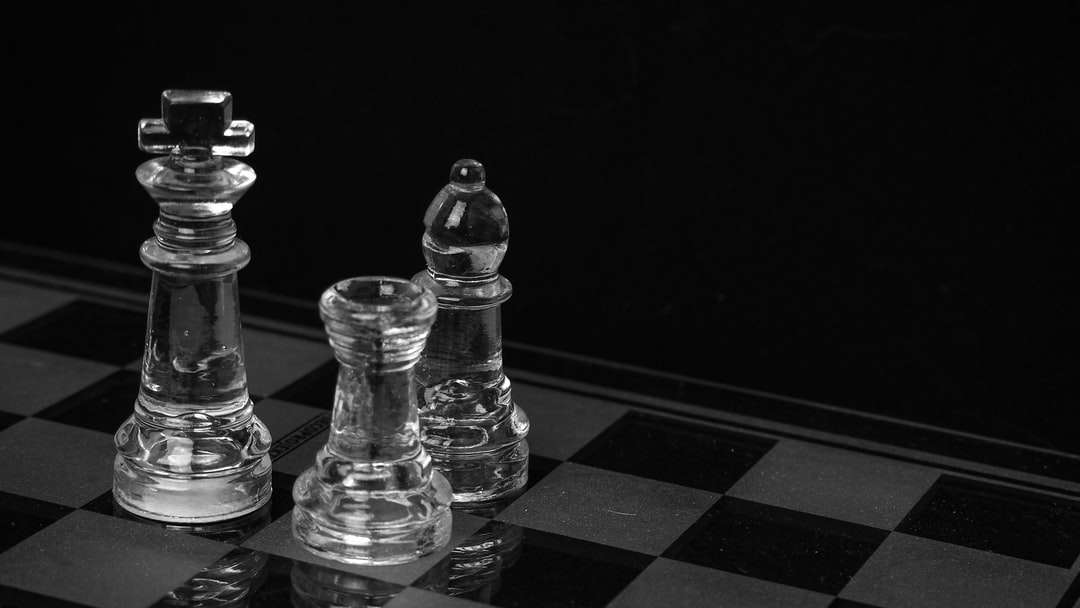 Pièce d'échecs en verre transparent sur la table en damier noir et blanc puzzle en ligne