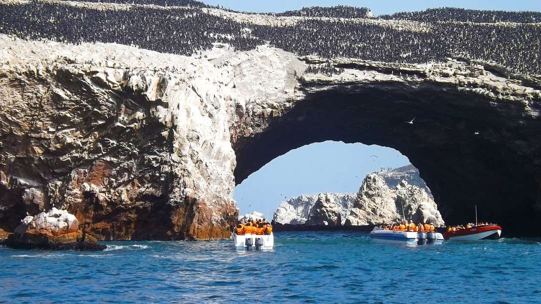 Fehér és narancssárga csónak a tenger közelében szürke sziklák kialakítása kirakós online