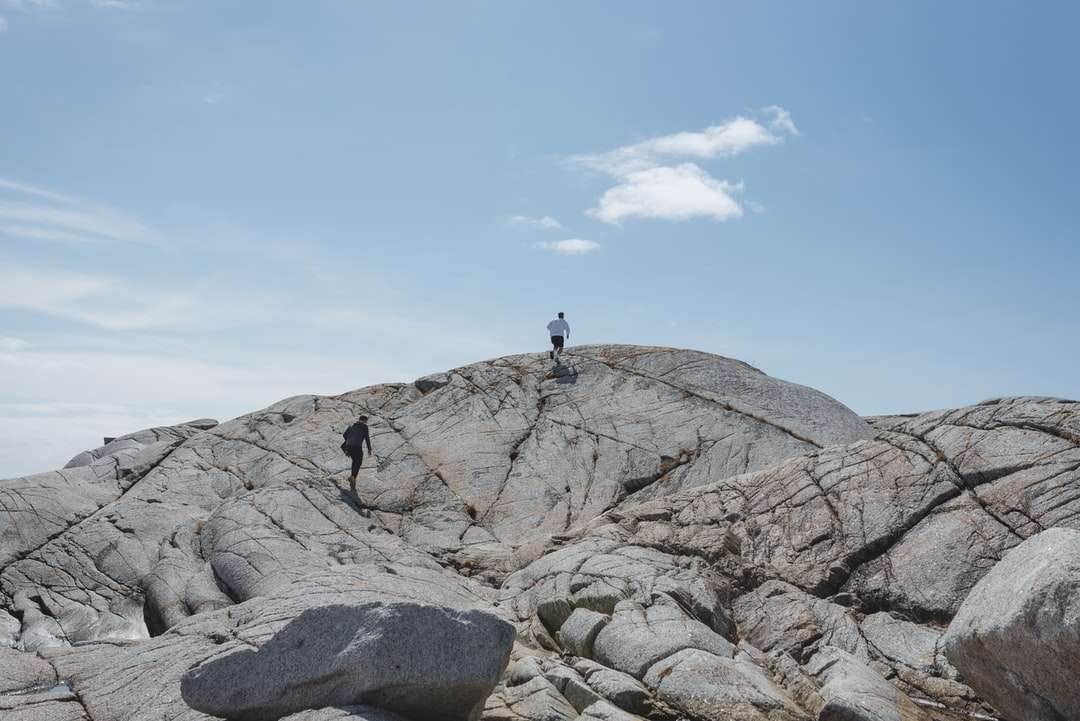 човек, който стои на скалист планина през деня онлайн пъзел