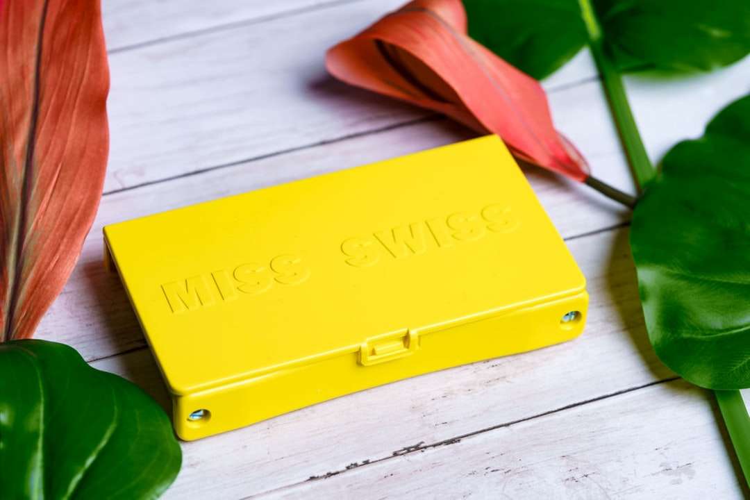 Caja de plástico amarilla en la mesa de madera blanca rompecabezas en línea