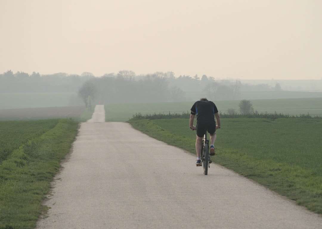 Човек в черната риза езда на велосипед на сив бетонен път онлайн пъзел