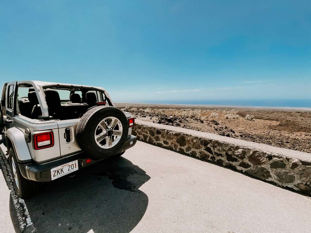 Λευκό και μαύρο SUV σε γκρίζα άμμο κάτω από τον μπλε ουρανό παζλ online