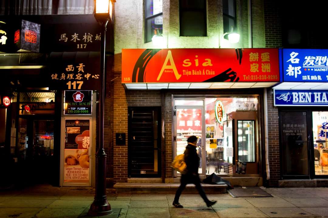 Az ember fekete kabátban sétál a járdán a Store közelében online puzzle