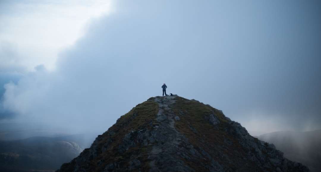 Persona de pie en la formación de roca bajo nubes blancas rompecabezas en línea