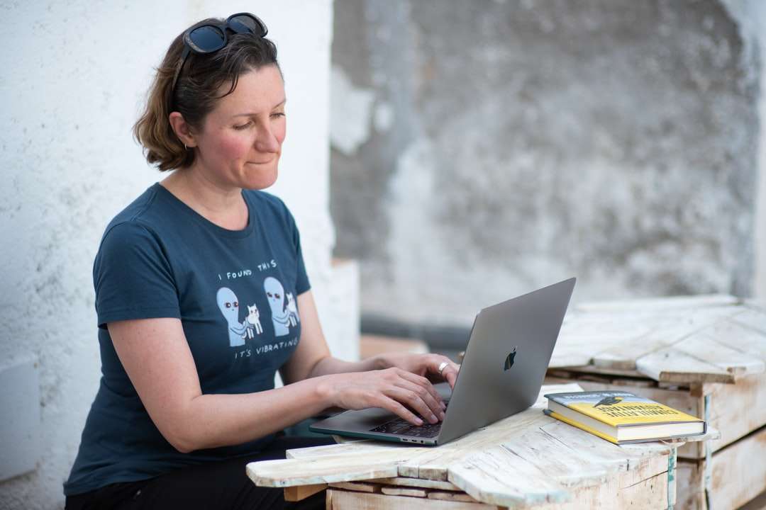 Femme en T-shirt au cou d'équipage bleu à l'aide de MacBook puzzle en ligne