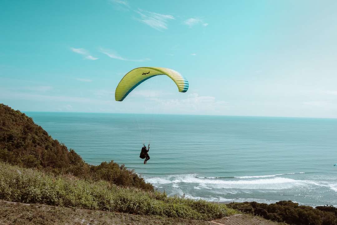 човек в черна риза на жълт парашут над синьото море онлайн пъзел