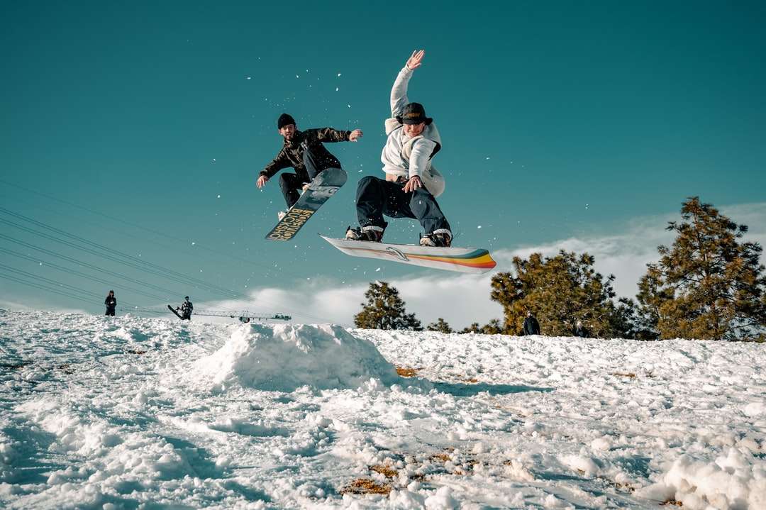 Man i svart och vitt jacka på snowboard Pussel online